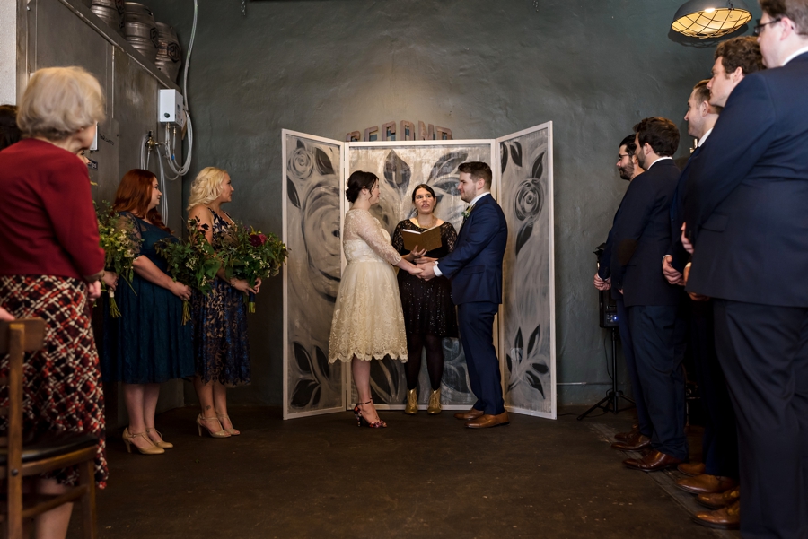A couple getting married in front of a home made painted screen.